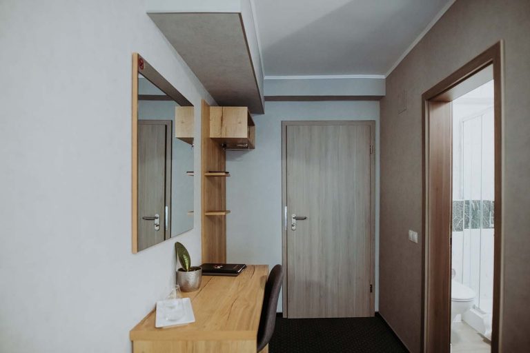 A small room with a bed and a desk available for cazare in Sibiu.