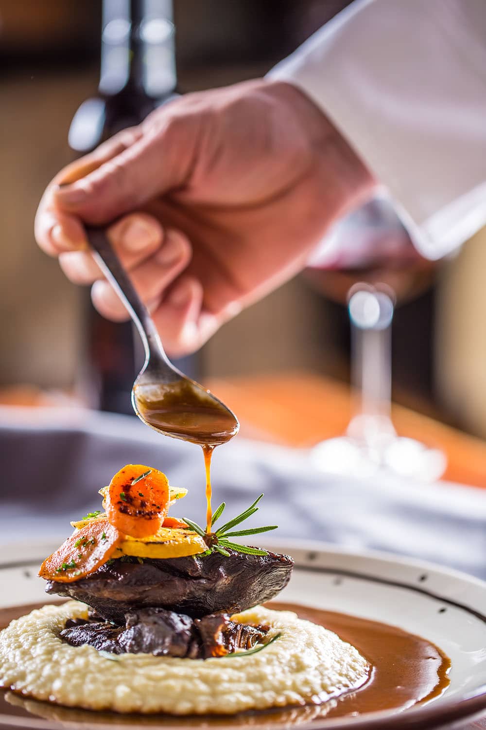 A chef drizzling sauce on a plate of food in Cisnadie.