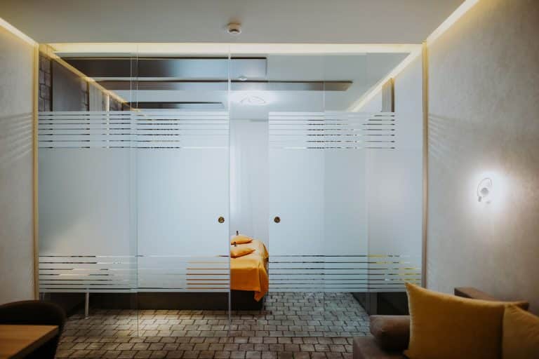A hotel room with a glass wall and a bed.