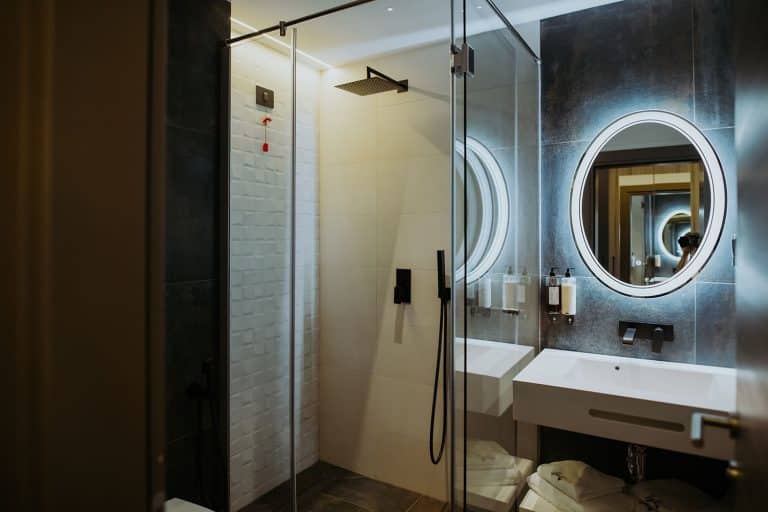 A hotel bathroom with a glass shower stall and mirror available for reservation in Sibiu.