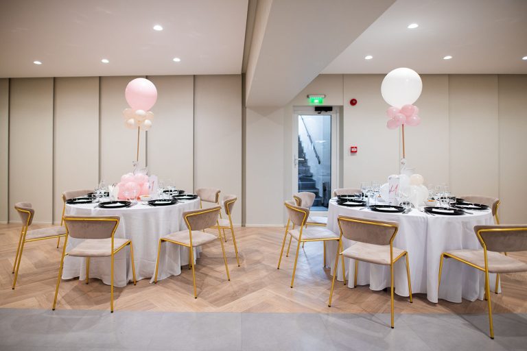 A table set up with balloons and white tablecloths in an Epic Harmony event space.