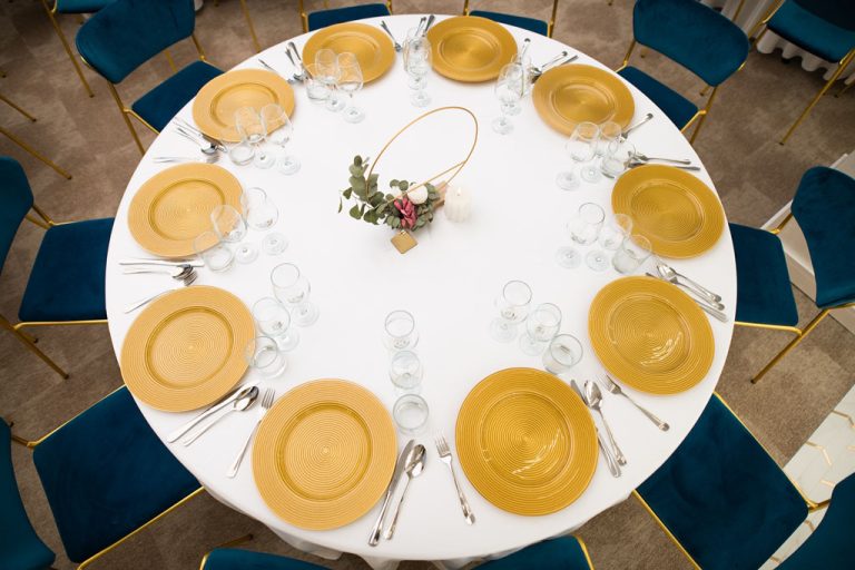 A table set with yellow plates and blue chairs at a hotel.