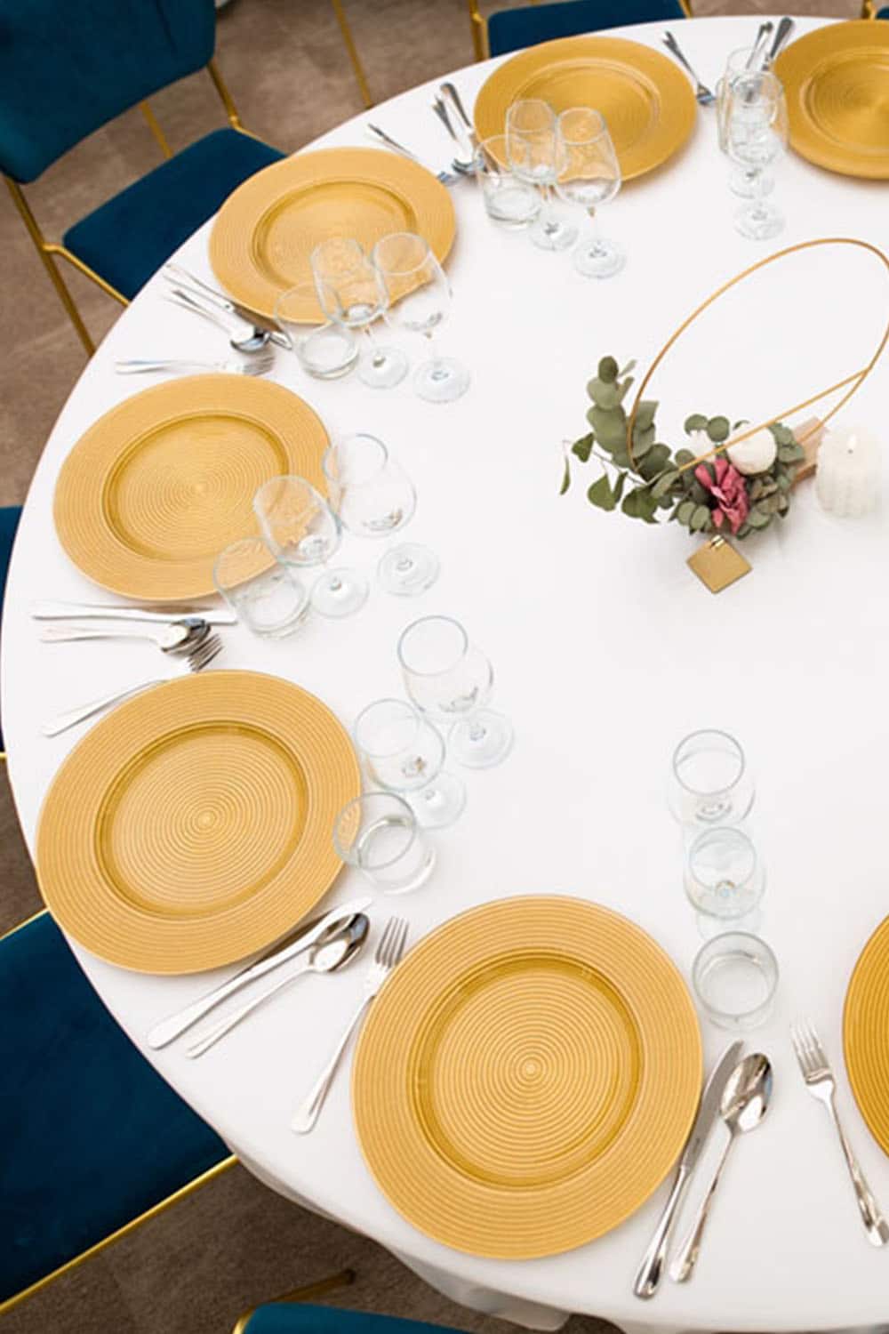 A round table with gold plates and silverware suitable for Sibiu visitors looking for accommodation.