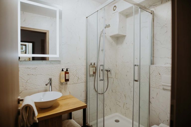 A hotel bathroom with a glass shower stall and sink available for reservation.