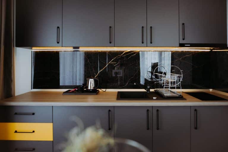 A hotel kitchen with black cabinets and yellow accents in Sibiu.