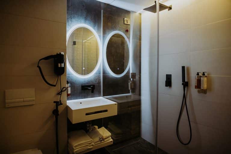 A hotel bathroom with two mirrors and a sink.