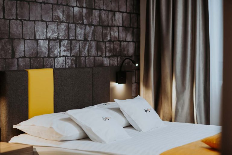 Descriere: Un pat într-o cameră de hotel cu accente galbene și negre.