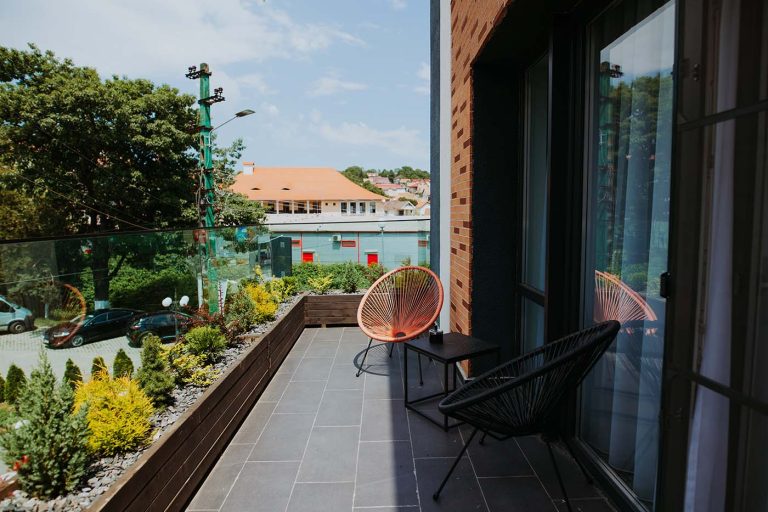A balcony with chairs and plants on it, perfect for a relaxing stay.