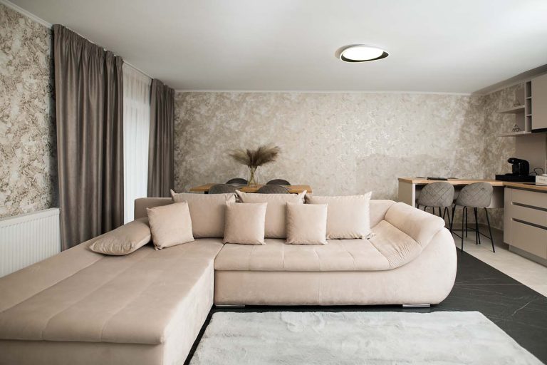 A hotel room with a beige couch and a kitchen in Sibiu.